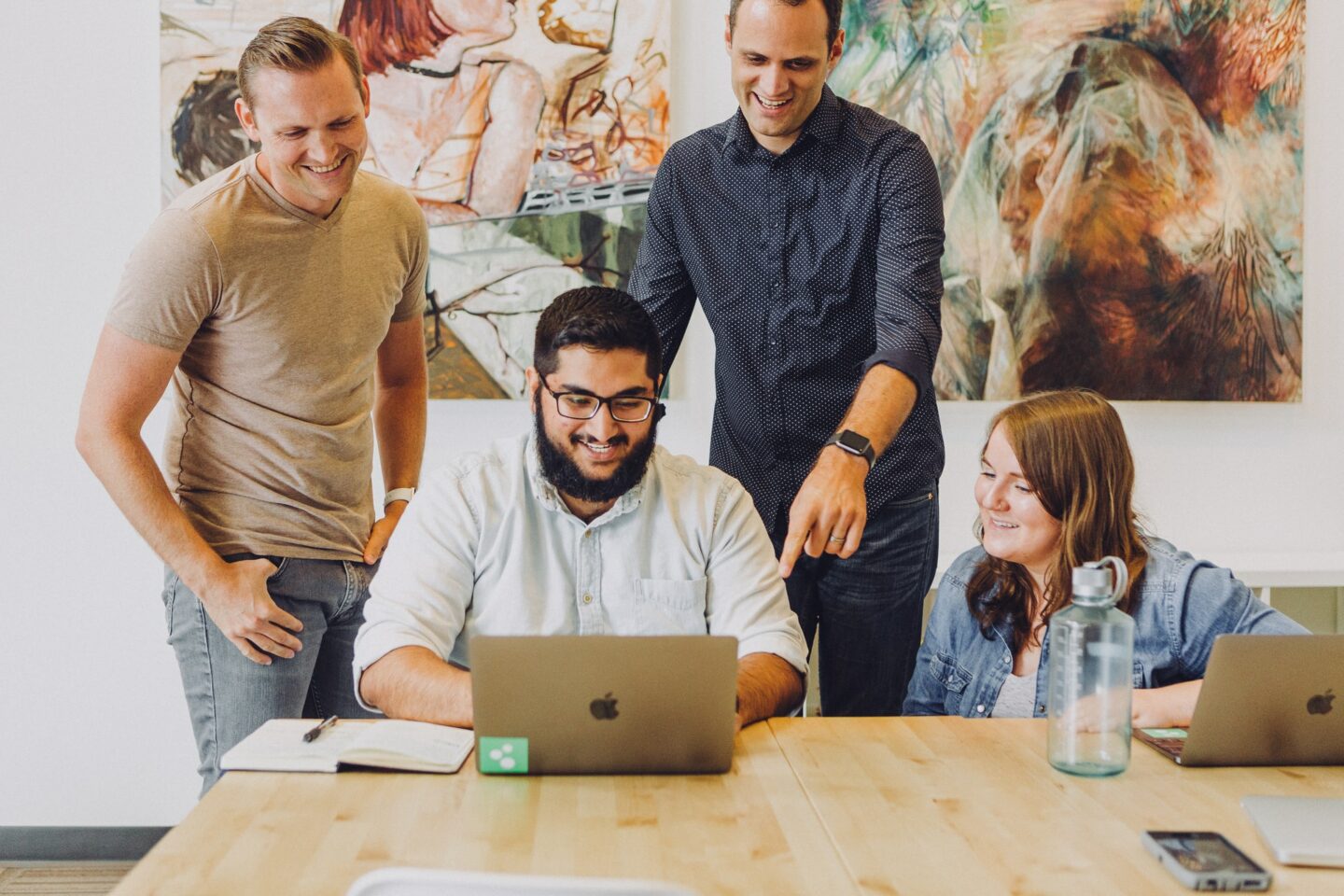 Photograph of four people looking at a laptop screen