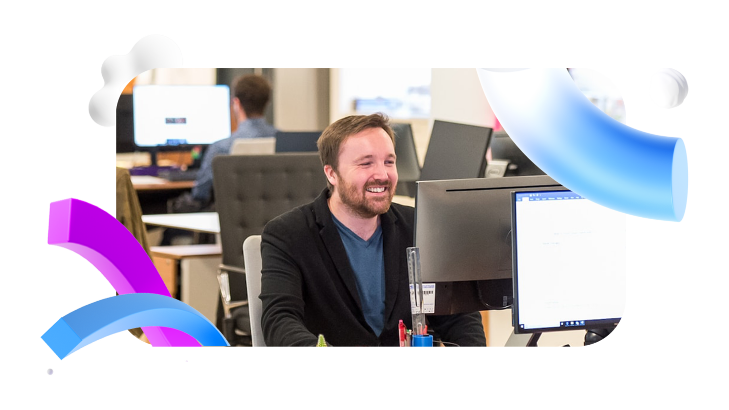 Man in front of a computer in an office smiling with Walr assets floating around the photograph