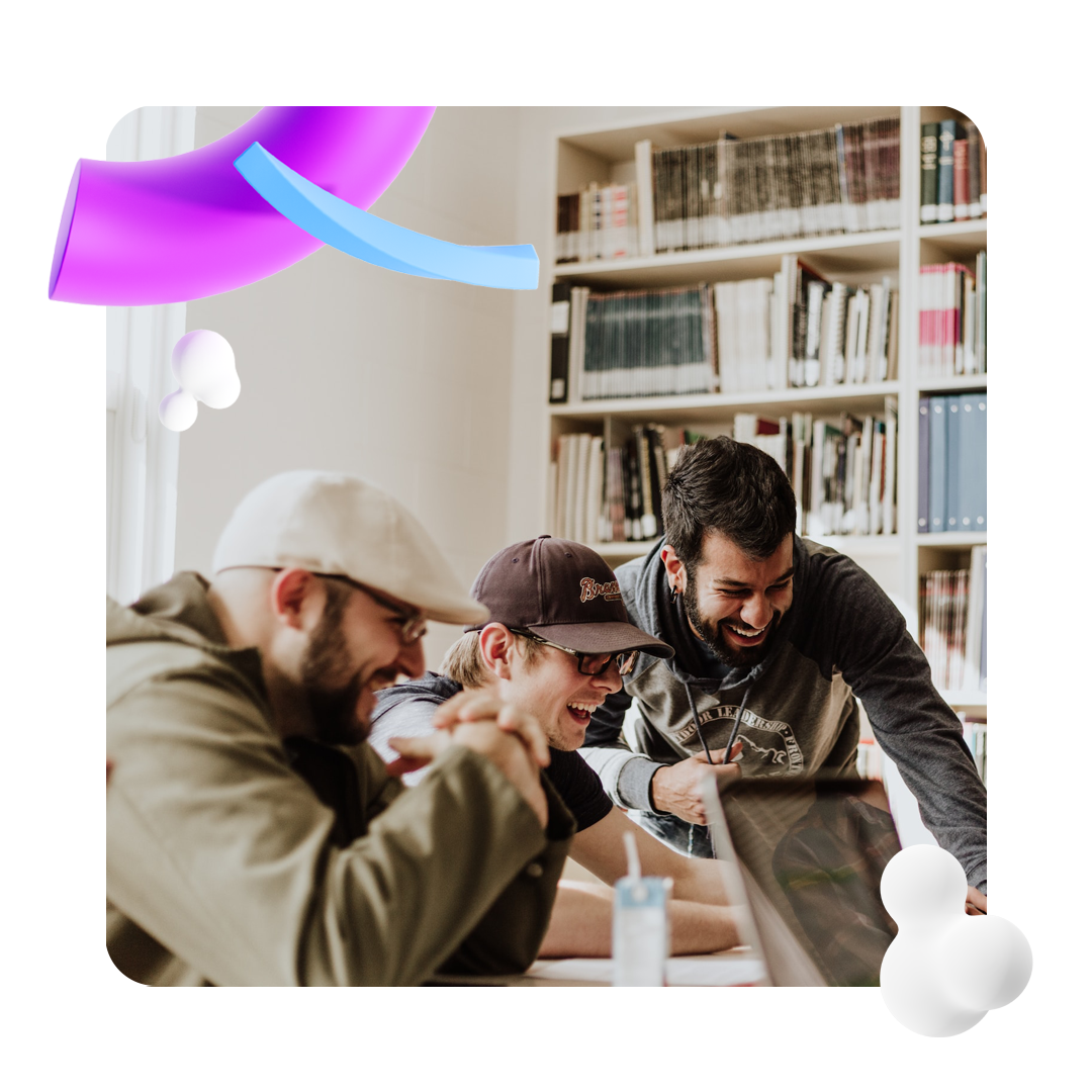 Three men laughing in front of a laptop screen