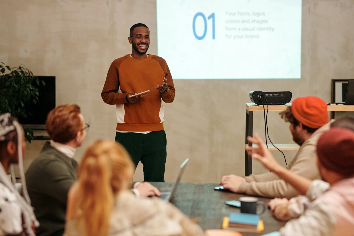 Person presenting in front of peers with a screen in the background