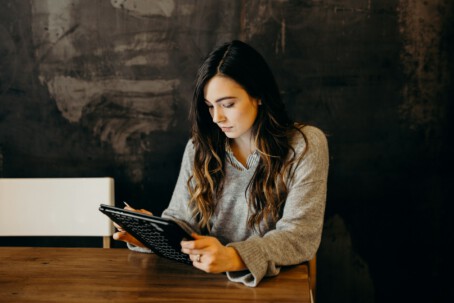 View How to Design a Good Survey and Avoid Respondent Fatigue A photograph of a woman sat on her own reading a tablet.