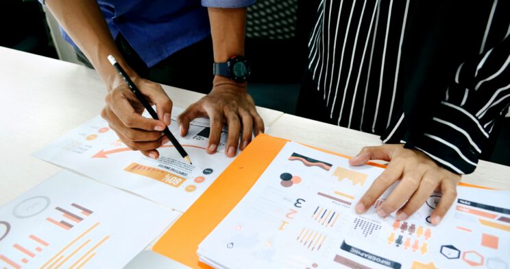 Two people annotating printed graphs and models