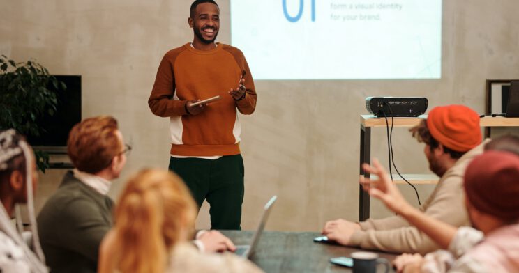 Person presenting in front of peers with a screen in the background
